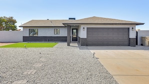 Une maison moderne de plain-pied, dotée d’un garage, d’une pelouse bien entretenue et d’une allée gravillonnée.