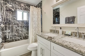 A bathroom with a bathtub, two sinks, a mirror, and a shower area.