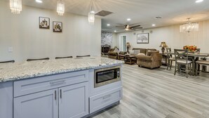 Une cuisine moderne dotée de plans de travail en granit, d’un four à micro-ondes encastré et de luminaires suspendus.