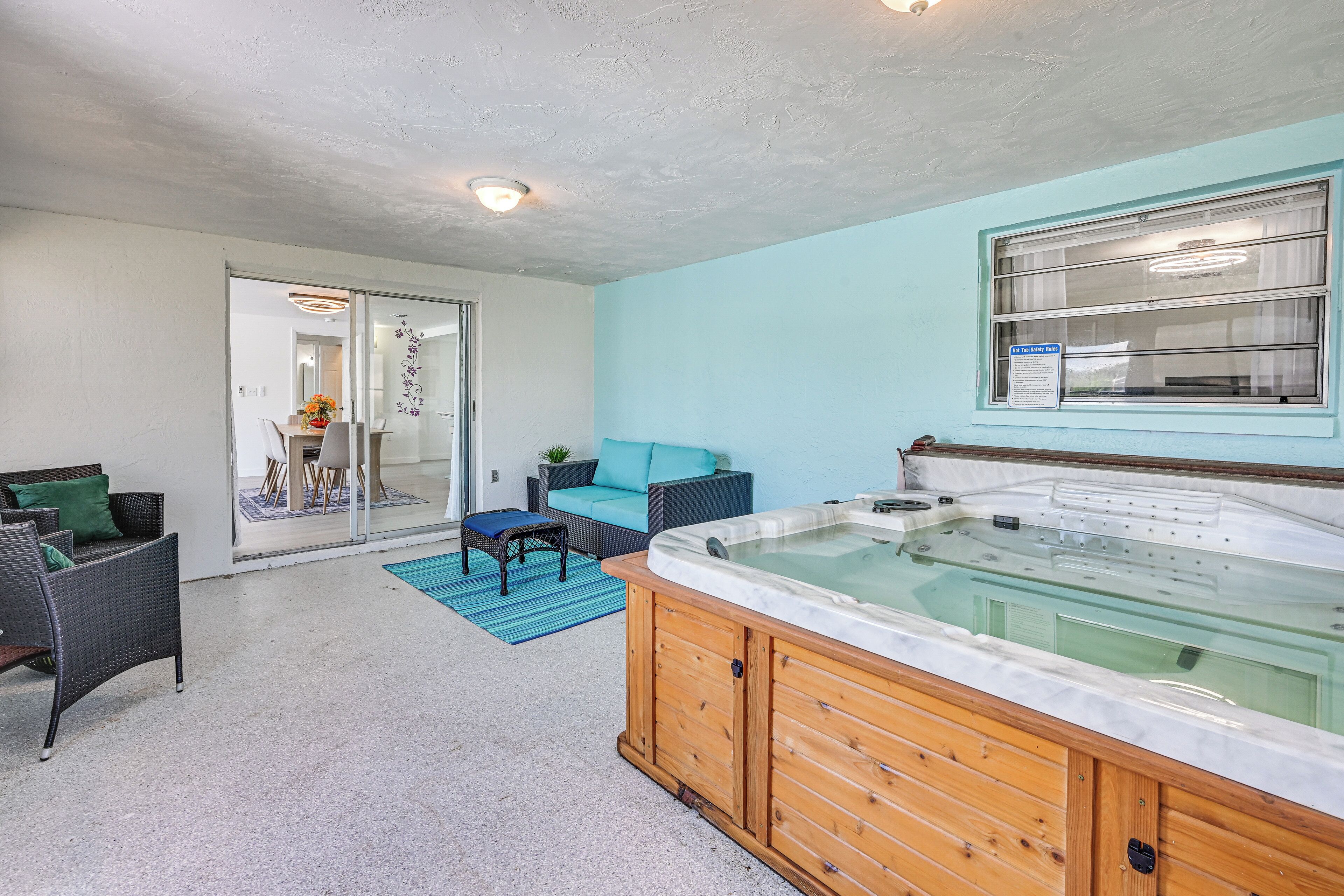 A modern interior with a wooden hot tub, a glass door leading to a dining area, and a teal accent wall.