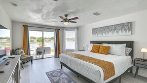 A modern bedroom with a large bed, a desk, and a view of the outdoors. - Sunset Views & Hot Tub: Lakefront Holiday Retreat! (Holiday)