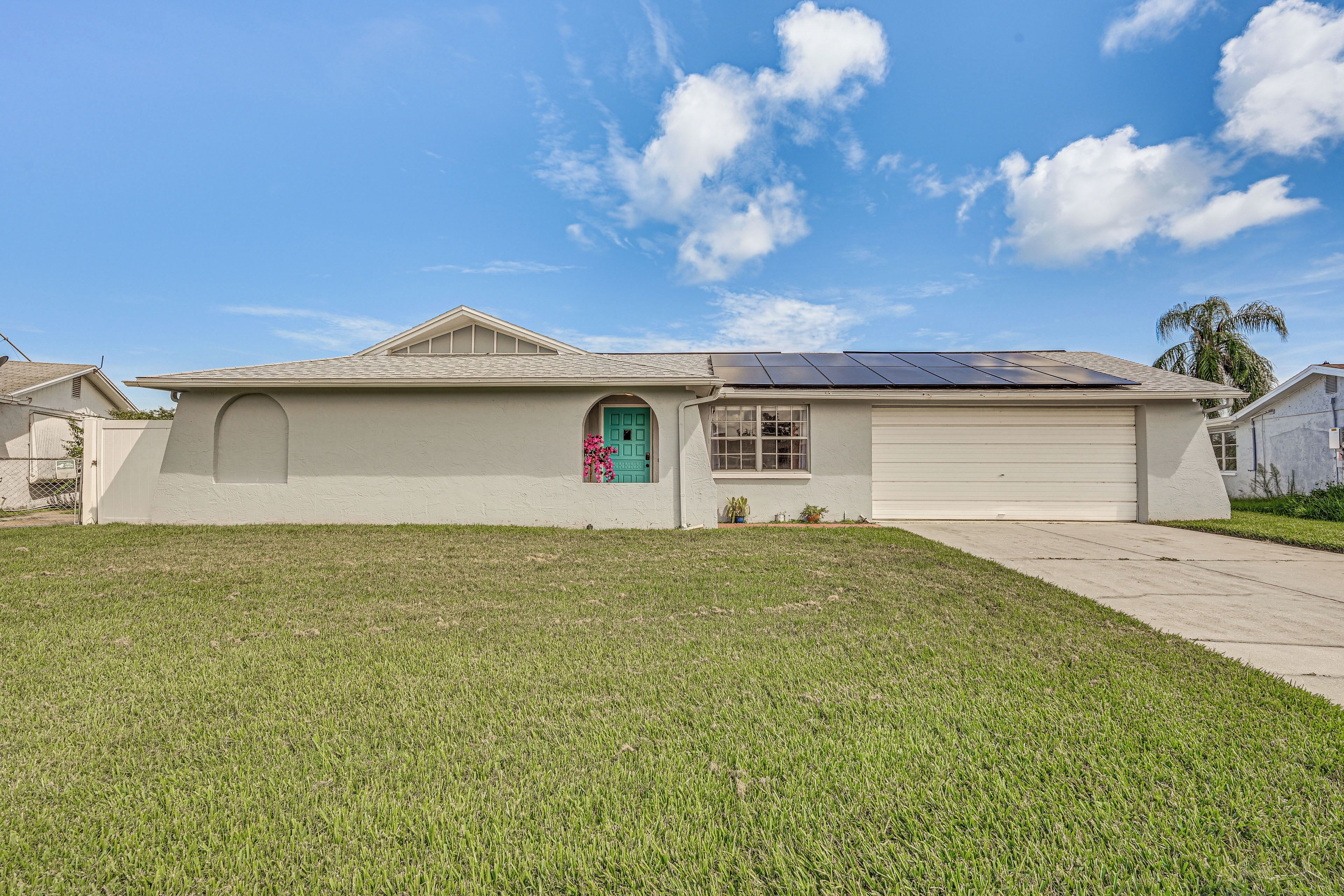 A single-story house with a front door, a small porch, and a solar panel on the roof.