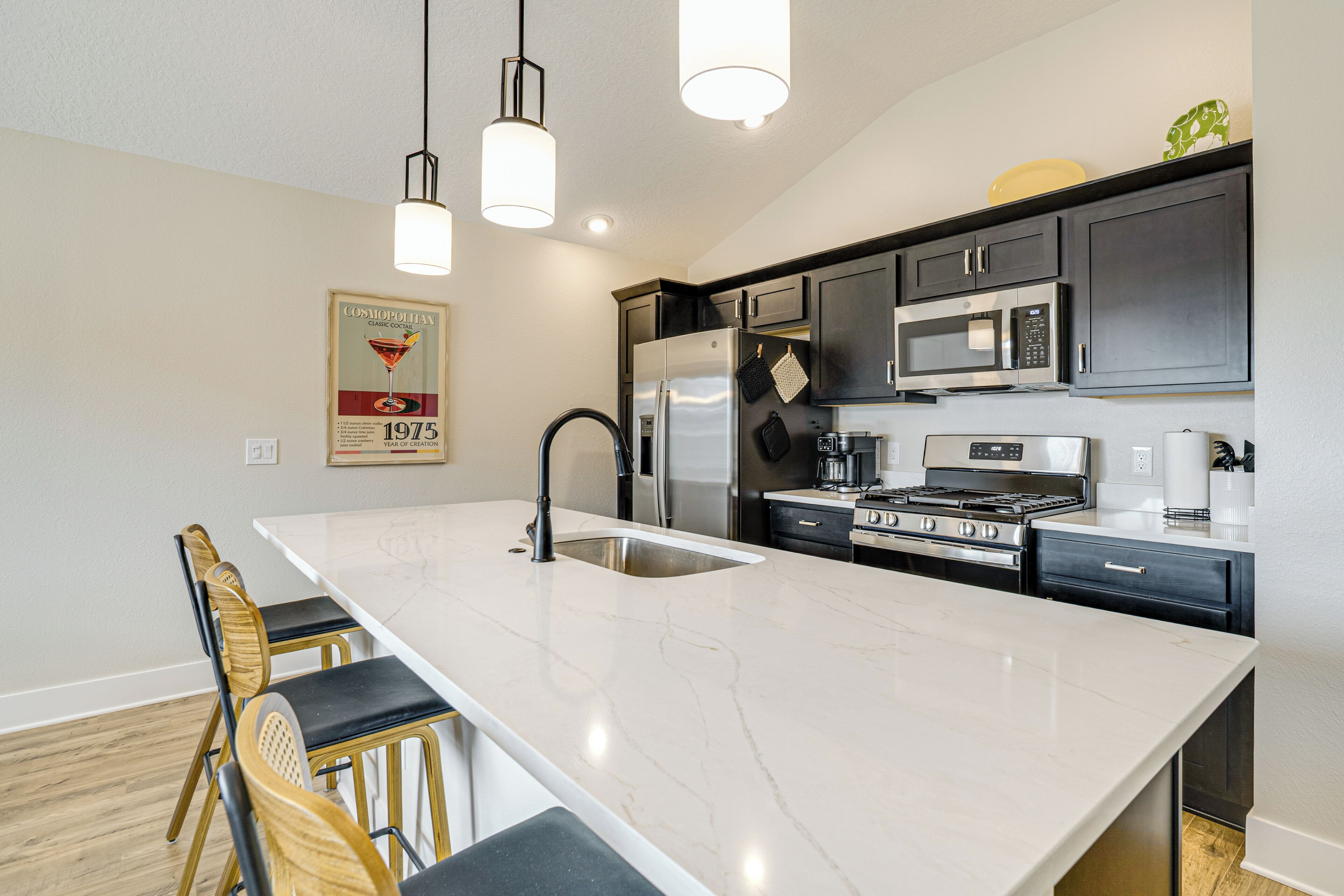 A modern kitchen with a large island, stainless steel appliances, and a bar stool seating area.