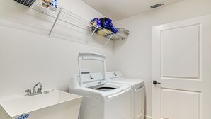 Un cuarto de lavandería con lavadora, secadora y lavabo.