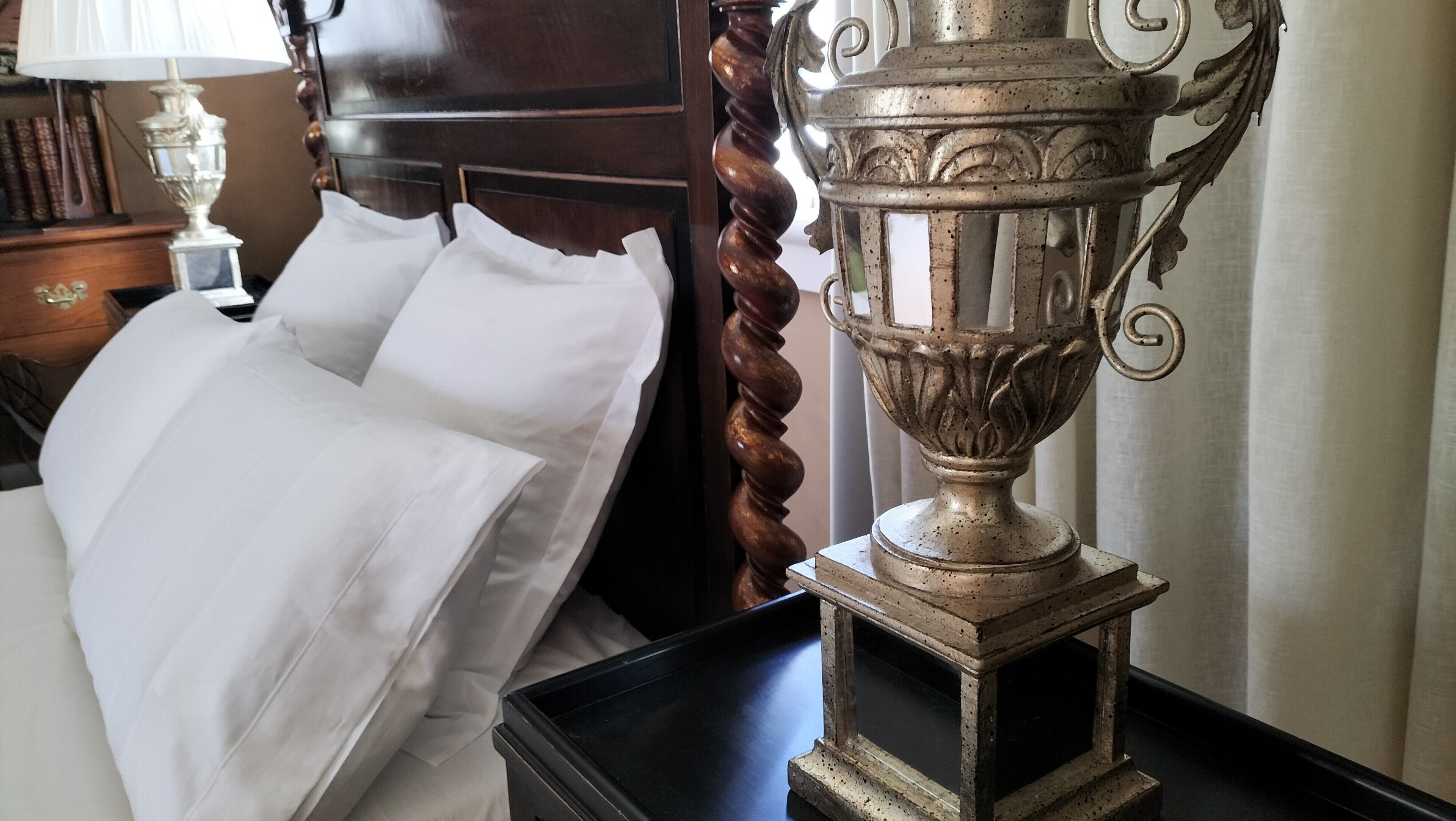 Una cama con sábanas blancas, un trofeo decorativo de metal y un cabecero de madera.