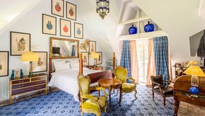 A hotel room with a bed, two chairs, a small table, a desk, a lamp, a mirror, and a chandelier. - Domaine de la Boisisère (Trouville-la-Haule)