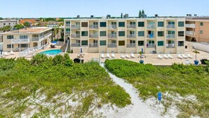 Un hôtel à étages, doté d’une piscine et d’un espace de plage avec des chaises longues.