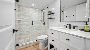Une salle de bain moderne avec une douche à parois de verre, des toilettes blanches et un meuble-lavabo avec un miroir.