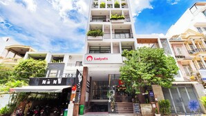 A multi-story building with balconies, a sign for 'Ladyfit', and a storefront with motorcycles. - Studio in Modern building with AC; Kitchen; 1.3km from TSN airport (Hồ Chí Minh)