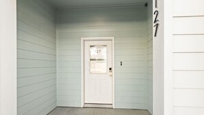 Una puerta blanca con un ventanal pequeño y un timbre.