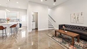 Una sala de estar moderna con un sofá, una mesa de centro y una escalera que lleva a otro nivel.