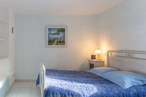 A bedroom with a bed, a nightstand with a lamp, and a painting on the wall.