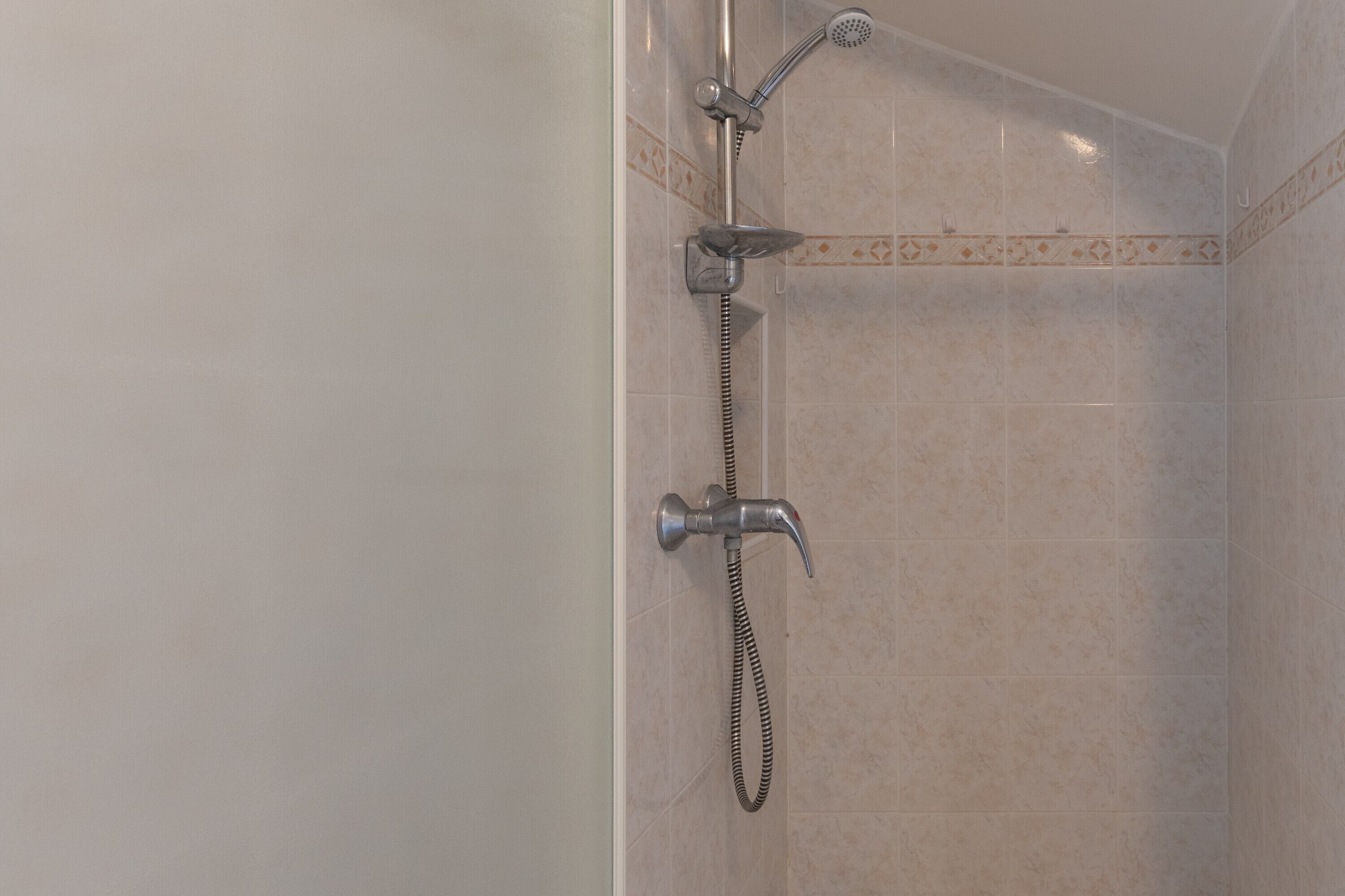Eine Dusche mit Handbrause und fest installiertem Wandarmatur.