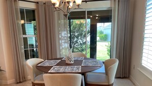 A dining area with a round table, four chairs, and a chandelier.