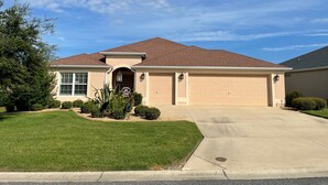 A single-story house with a brown roof, beige exterior walls, and a garage.