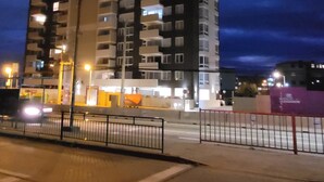 Un immeuble de grande hauteur doté de nombreux balcons, une rue avec un feu de signalisation et un passage piéton.