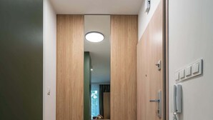 Un couloir avec des portes en bois, un téléphone et un luminaire.