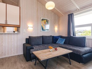 A modern living room with a sectional sofa, a wooden coffee table, and a painting on the wall. - 4 Star Holiday Home in Friedrichskoog (Friedrichskoog)