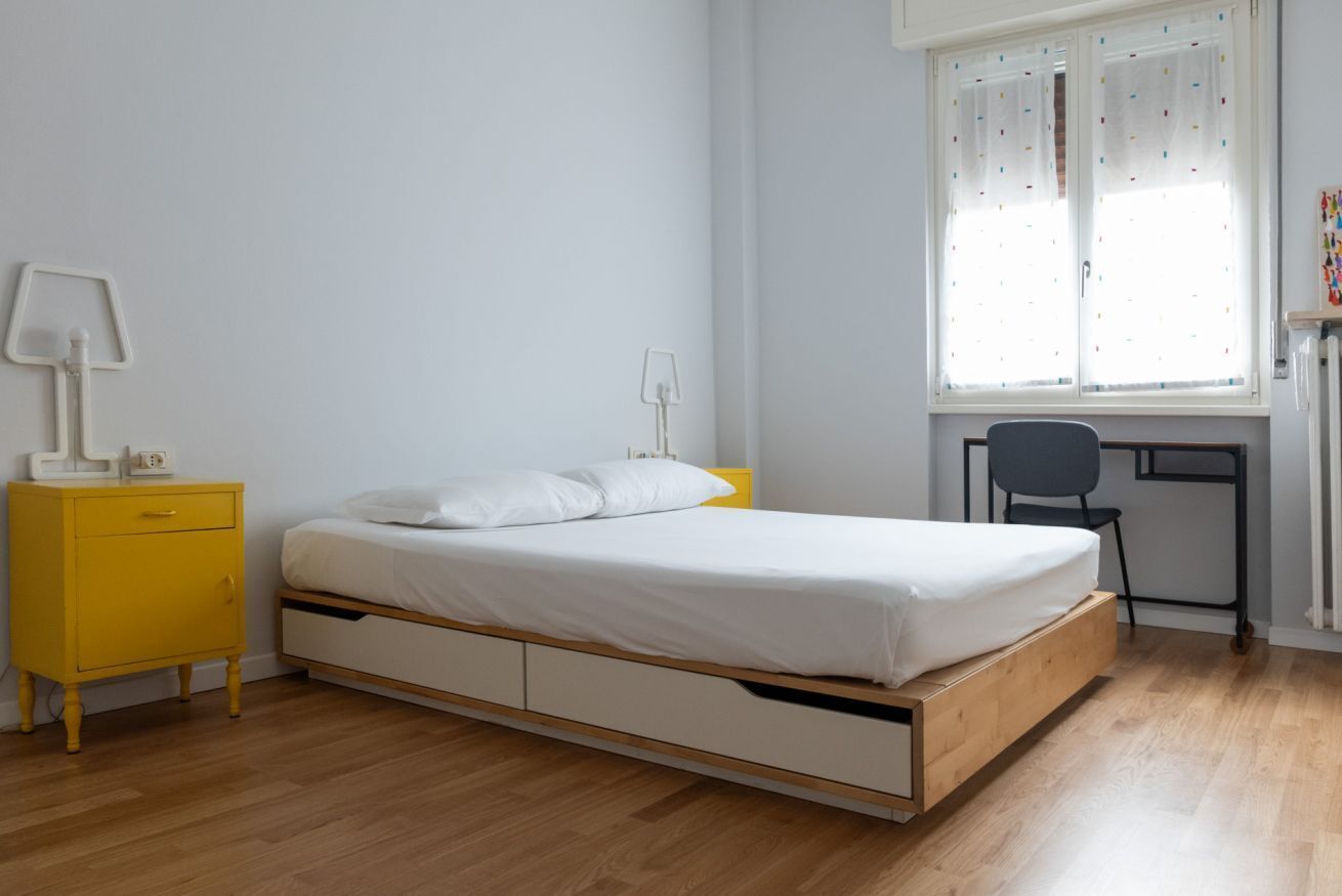 A bedroom with a bed, a desk, and a chair.