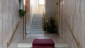 Una escala de marbre amb un aterradora cobert de catifes vermelles, flanquejada per dues baranes de bronze que condueixen a un pis superior.