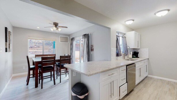 A modern kitchen with white cabinetry, a granite countertop, and a built-in dishwasher. - Spacious Family Home in Denver with large yard (Denver)