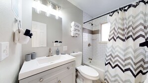 A modern bathroom with a white vanity, a shower, and a chevron-patterned shower curtain. - Spacious Family Home in Denver with large yard (Denver)