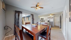 A dining area with a wooden table and chairs, a ceiling fan, and a view into a kitchen with modern appliances. - Spacious Family Home in Denver with large yard (Denver)