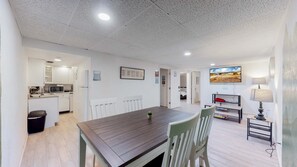 A spacious living area with a dining table, a kitchen in the background, and a TV mounted on the wall. - Spacious Family Home in Denver with large yard (Denver)