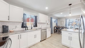 A modern kitchen with white cabinets, a stainless steel dishwasher, and a granite countertop. - Affordable four bedroom Family Denver home (Denver)
