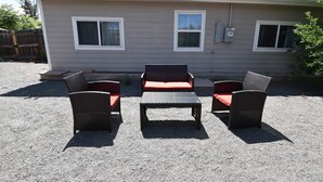 A mobile home with a patio area featuring wicker furniture and a table.