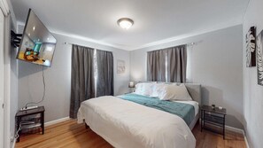 A bedroom with a bed, a TV mounted on the wall, a bedside table, and a nightstand. - Unique Family Home in Denver (Denver)