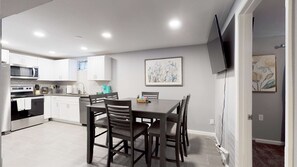 A modern kitchen with white cabinets, a built-in oven, and a dining area with a table and chairs. - Unique Family Home in Denver (Denver)