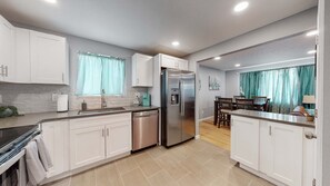 Una cocina moderna con armarios blancos, electrodomésticos de acero inoxidable y lavavajillas.
