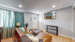 A living room with a sofa, coffee table, and a TV mounted on the wall. - Unique Family Home in Denver (Denver)