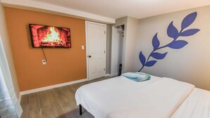 A hotel room with a bed, a television mounted on the wall, and a decorative wall piece.