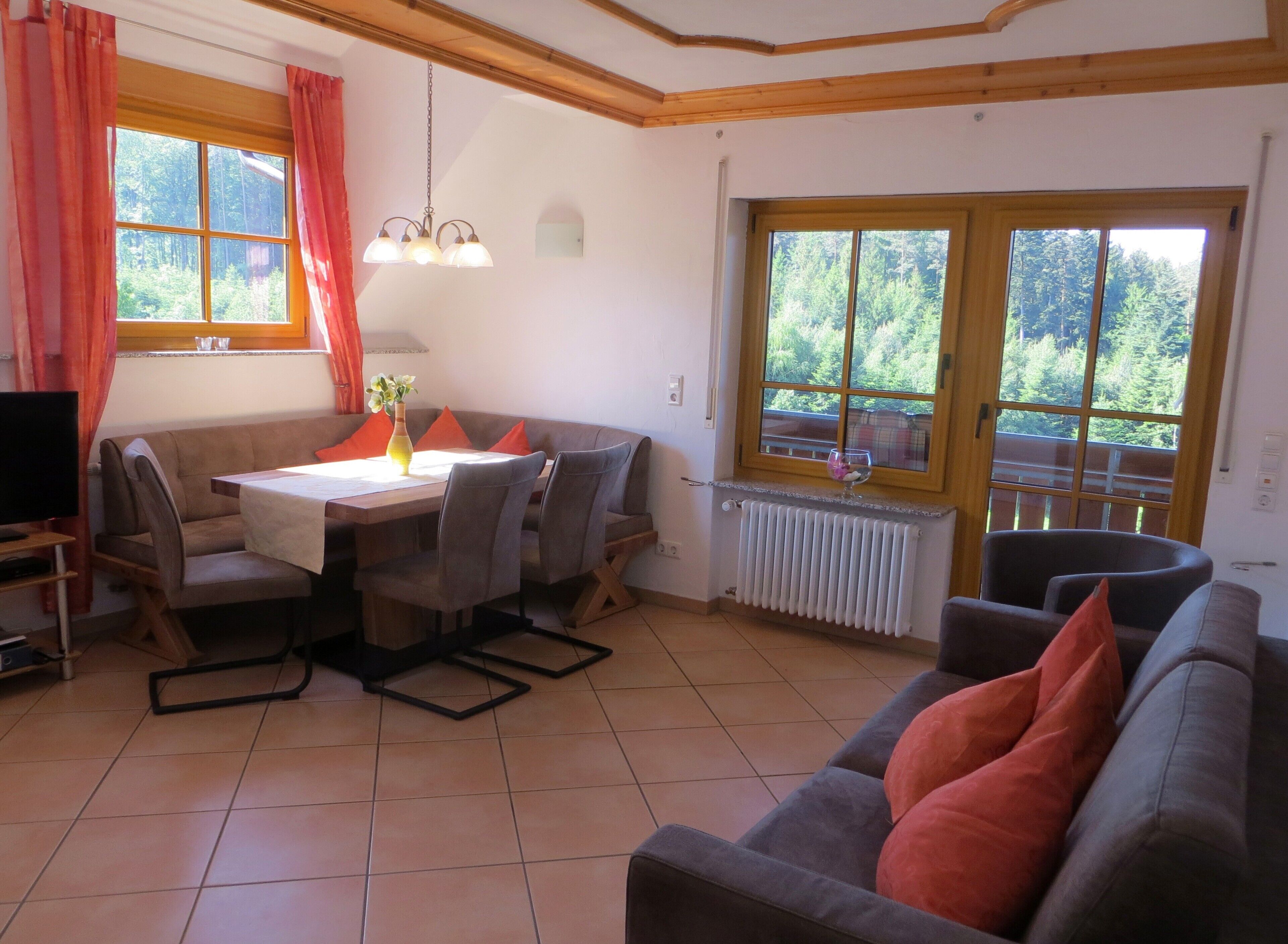 A dining area with a table, chairs, a sofa, and a TV.