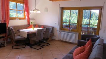 A dining area with a table, chairs, a sofa, and a TV.