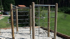 A playground with a wooden swing set and metal chains. - Holiday Apartment 'Landsitz, 55 sqm' with Shared Terrace, Shared Garden and Wi-Fi (Elzach)