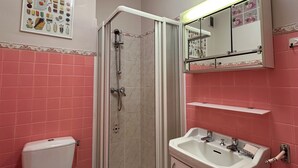 Een badkamer met toilet, douchecabine, wastafel en spiegel.