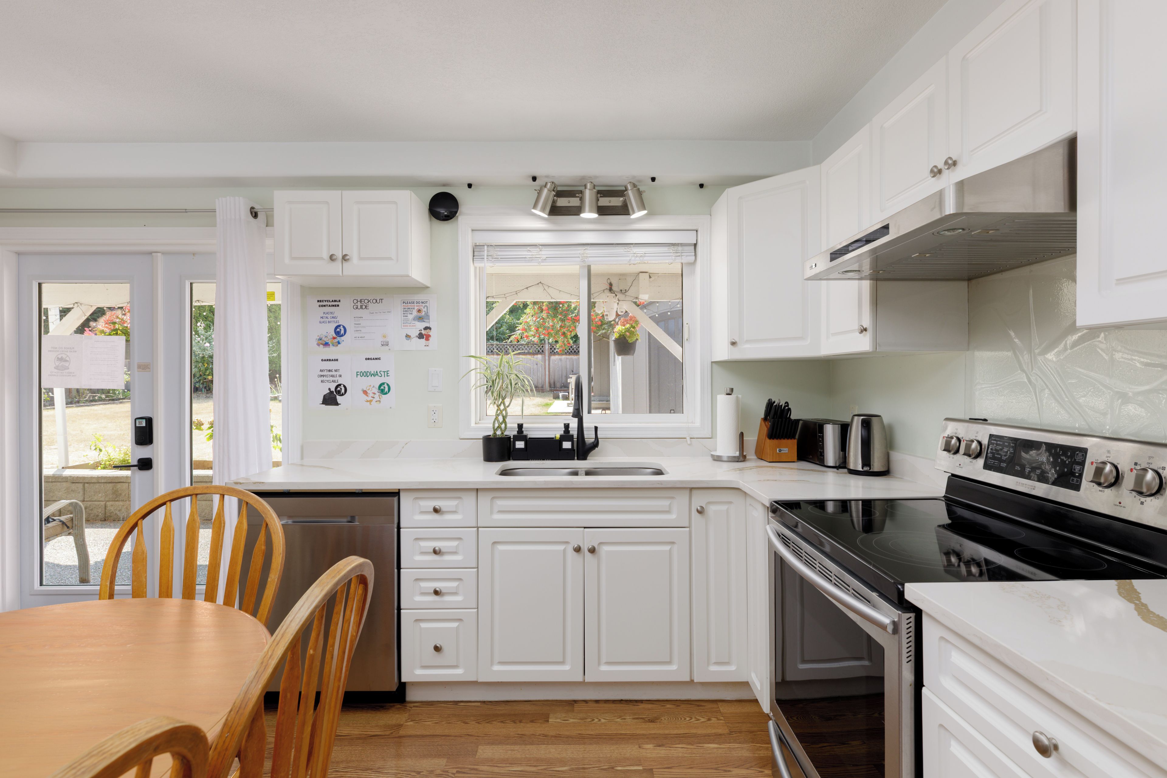 Une cuisine avec des meubles blancs, une cuisinière noire et une table à manger en bois.