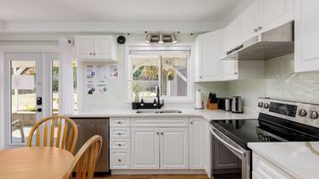 A kitchen with white cabinets, a black stove, and a wooden dining table.