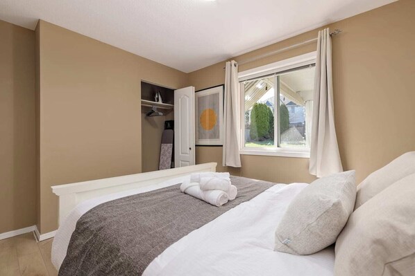 A bedroom with a bed, a window with curtains, a wardrobe, and a radiator.