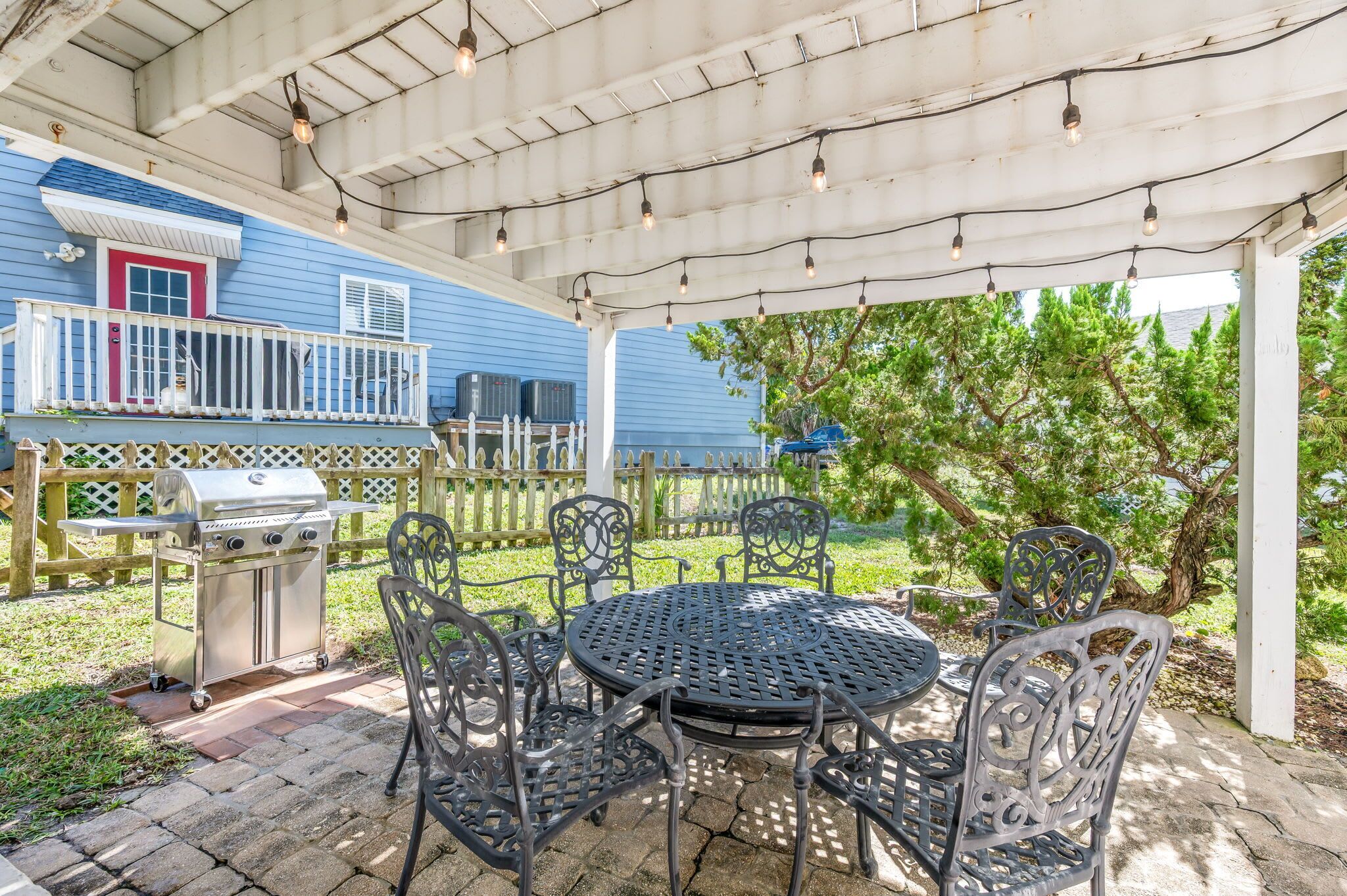 An outdoor patio with a grill, metal chairs, and a table.