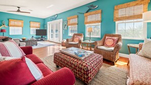 Una sala de estar con paredes color turquesa, muebles de mimbre y un sofá rojo.