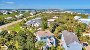 Vista aérea de una zona residencial costera con casas, carreteras y una playa al fondo.