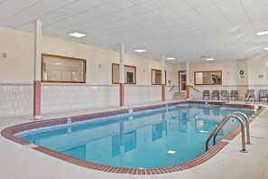 Una piscina interior con agua cristalina, paredes y piso de baldosas.