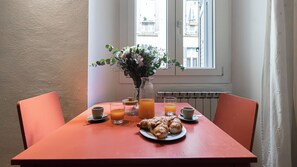 A breakfast table with croissants, juice, and a vase of flowers.