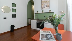 Eine moderne Küche mit weißen Schränken, einer grünen Spritzschutzwand und einem Essbereich mit Tisch und Stühlen.
