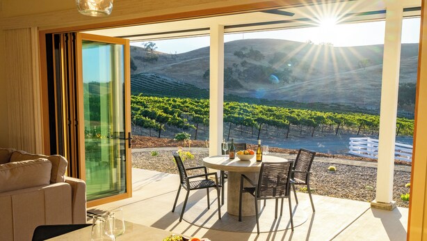 A dining area with a table set for two, overlooking a vineyard. - Vineyard Views + Covered Patio | Paso Robles | Mission de los Robles (Paso Robles)