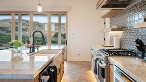 A modern kitchen with a large island, a gas stove, and a view of the outdoors. - Vineyard Views + Covered Patio | Paso Robles | Mission de los Robles (Paso Robles)
